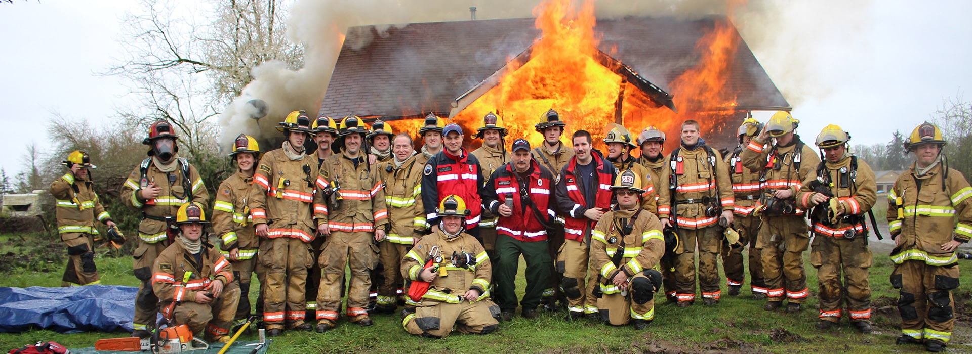 A group of Molalla firefighters standing in front of a training burn at a home donated to the fire district for training
